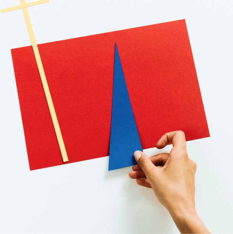 A right palm placing a blue paper cut out over a red paper sheet