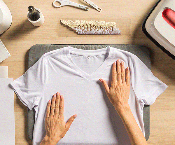 Top view of a spread t-shirt and Cricut machines on a desk