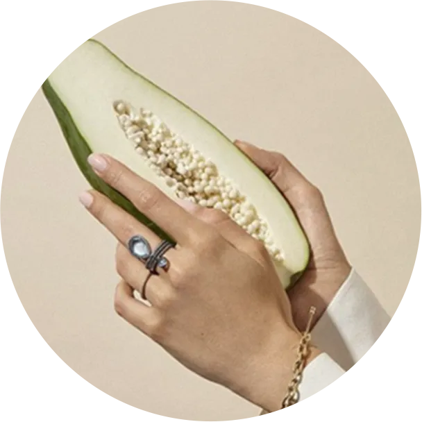 Hands with a ring and a brecelet holding a papaya
